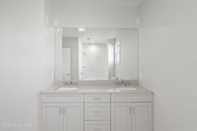 bathroom featuring double vanity and tiled shower