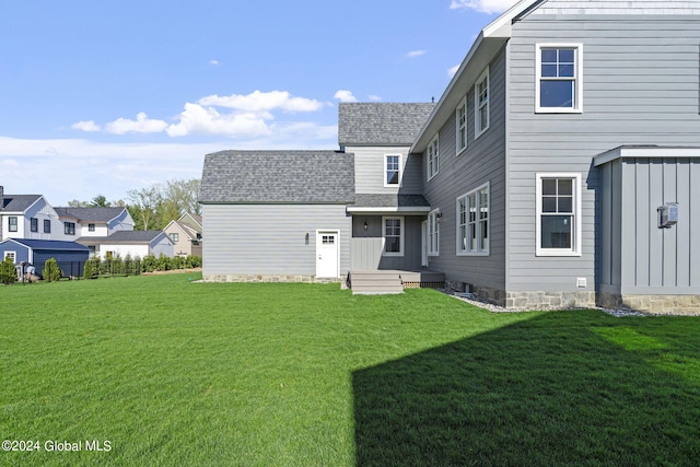 rear view of house with a lawn and a shingled roof