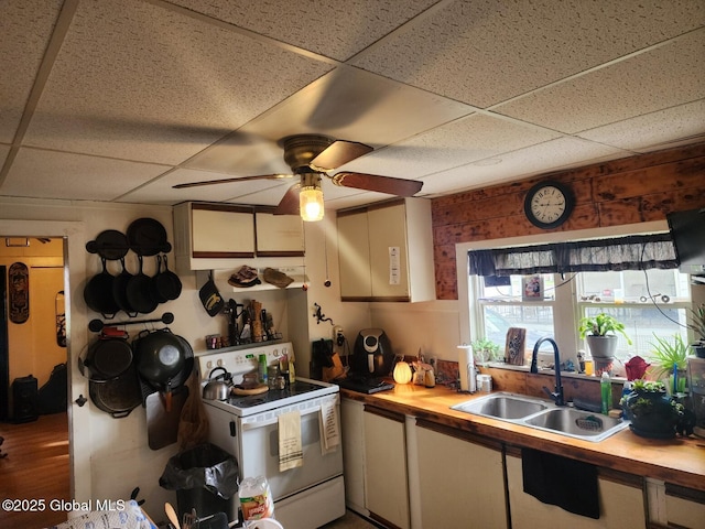 kitchen with wood counters, a drop ceiling, white electric range, and a sink