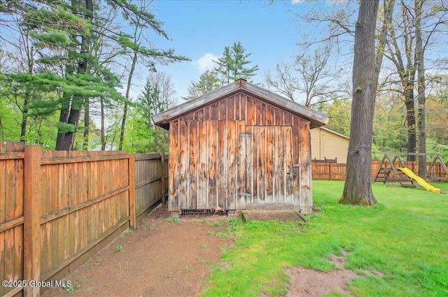view of shed featuring a playground and a fenced backyard