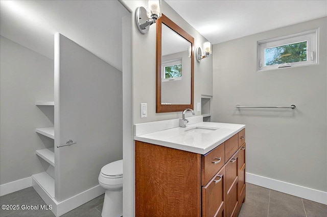 bathroom with baseboards, tile patterned flooring, vanity, and a healthy amount of sunlight