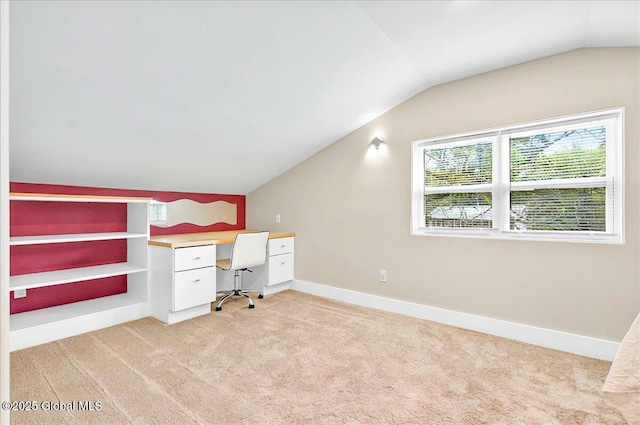 unfurnished office featuring light carpet, lofted ceiling, and baseboards