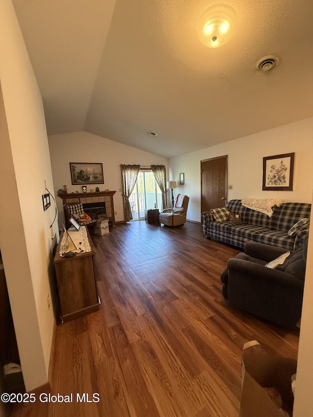 living room featuring wood finished floors, vaulted ceiling, and a tile fireplace