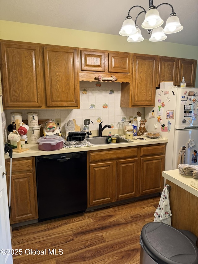 kitchen with black dishwasher, a sink, freestanding refrigerator, light countertops, and a chandelier