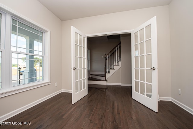 empty room featuring baseboards, french doors, and dark wood-style floors