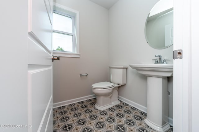 bathroom with a sink, toilet, and baseboards