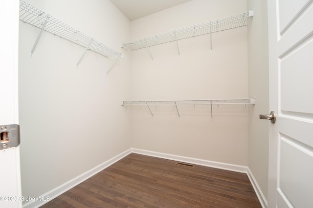 walk in closet with dark wood-style flooring and visible vents
