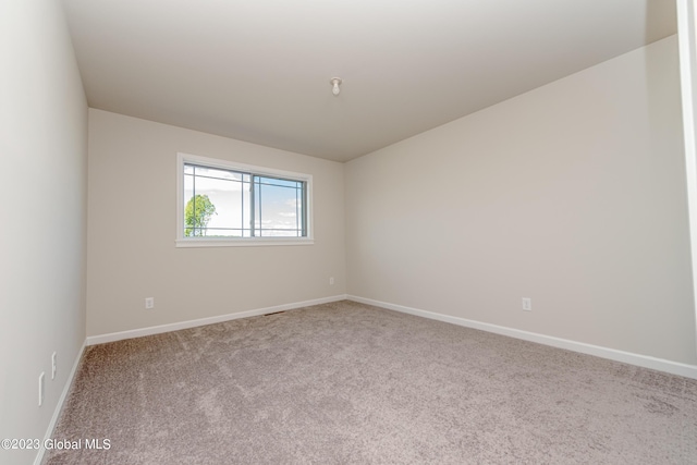 carpeted spare room featuring baseboards