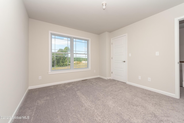 empty room with carpet flooring, baseboards, and visible vents