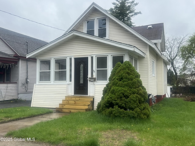 bungalow featuring entry steps, roof with shingles, and a front lawn