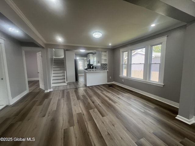unfurnished living room with ornamental molding, stairway, baseboards, dark wood-style floors, and recessed lighting