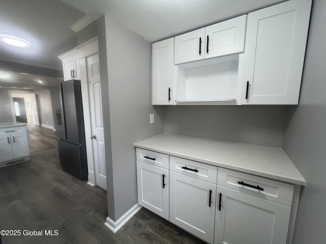 kitchen featuring stainless steel refrigerator with ice dispenser, dark wood-type flooring, white cabinetry, baseboards, and light stone counters