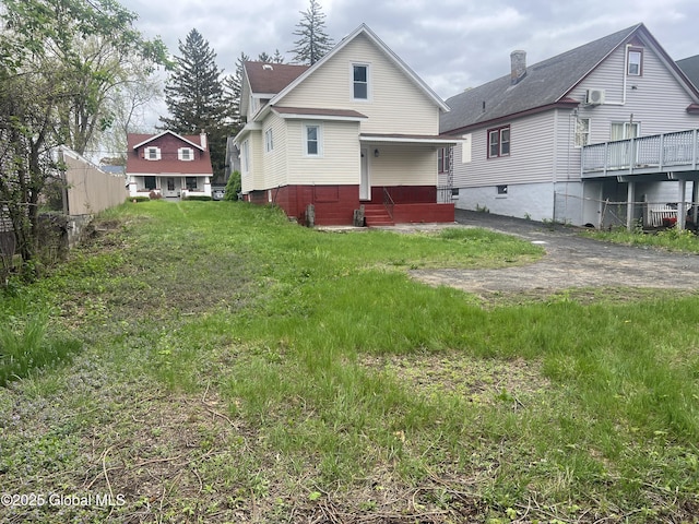 back of house with a chimney and roof with shingles