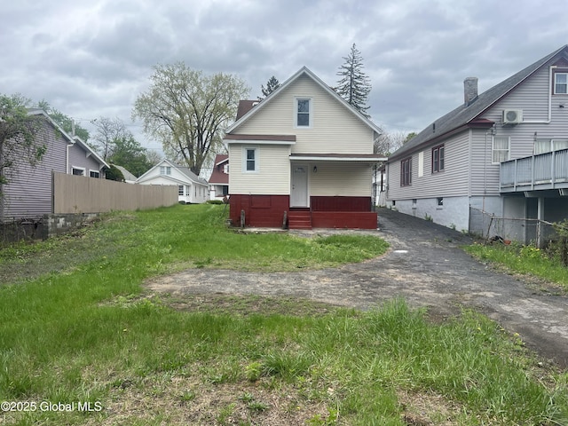 rear view of house featuring fence, entry steps, and a chimney