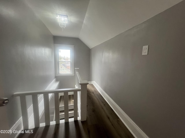 stairway featuring wood finished floors, baseboards, and lofted ceiling