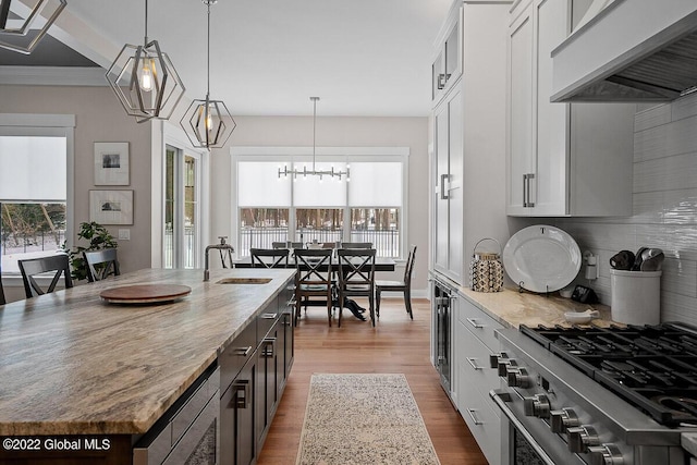 11 Forest Hills Blvd, North Greenbush, NY 12144 - kitchen with wall chimney range hood, a sink, appliances with stainless steel finishes, wood finished floors, and light stone countertops