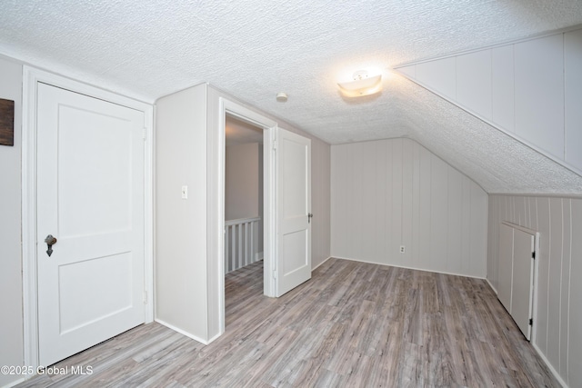 bonus room featuring a textured ceiling and light wood-style floors