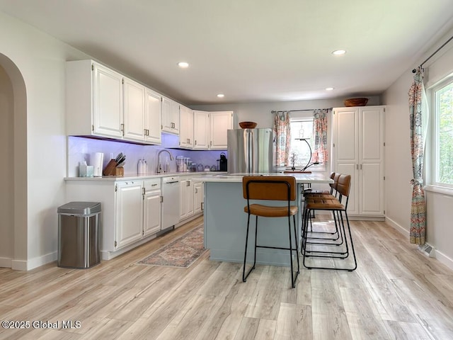 233 Cleverdale Rd, Queensbury, NY 12804 - kitchen with freestanding refrigerator, arched walkways, white cabinetry, light countertops, and a center island