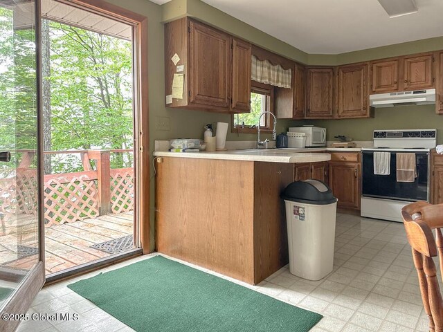 233 Cleverdale Rd, Queensbury, NY 12804 - kitchen with under cabinet range hood, electric stove, a sink, light countertops, and a peninsula