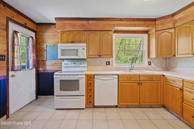 kitchen featuring white appliances, a sink, wood walls, light countertops, and light tile patterned floors