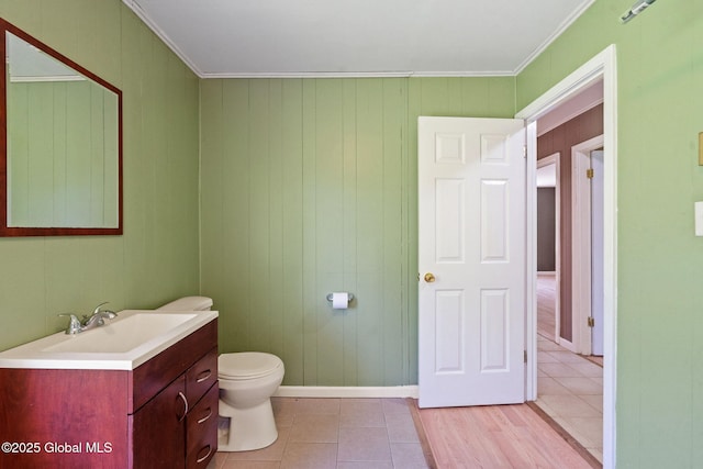 bathroom with toilet, crown molding, vanity, tile patterned flooring, and baseboards