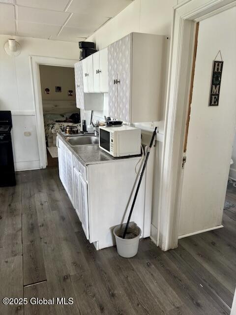 11 Lefferts St, Amsterdam, NY 12010 - kitchen with white microwave, black range oven, dark wood-style flooring, and white cabinets