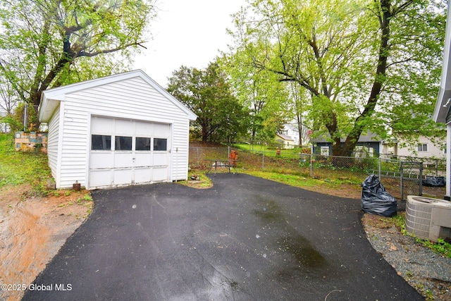 detached garage featuring central AC unit, fence, and driveway