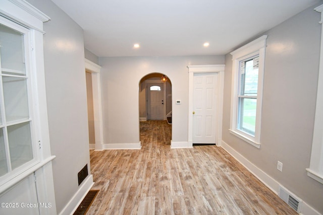hall with recessed lighting, baseboards, visible vents, wood finished floors, and arched walkways