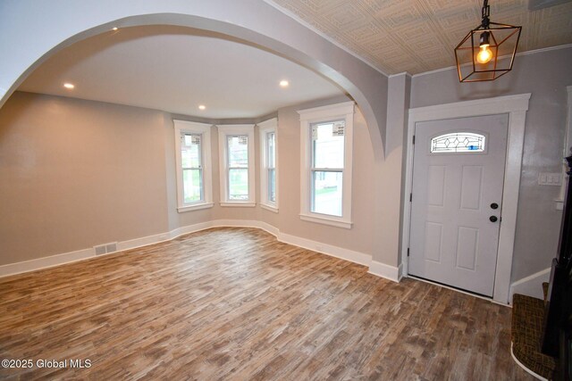entrance foyer featuring wood finished floors, visible vents, baseboards, arched walkways, and recessed lighting