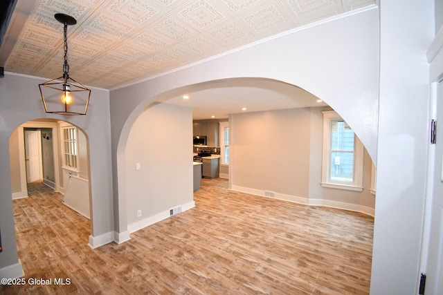 spare room with crown molding, light wood-style flooring, and an ornate ceiling