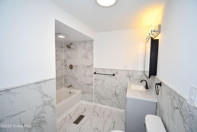 bathroom with toilet, washtub / shower combination, tile walls, marble finish floor, and vanity