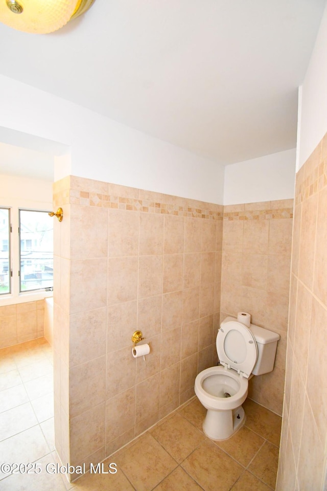 bathroom with toilet, tile walls, and tile patterned floors