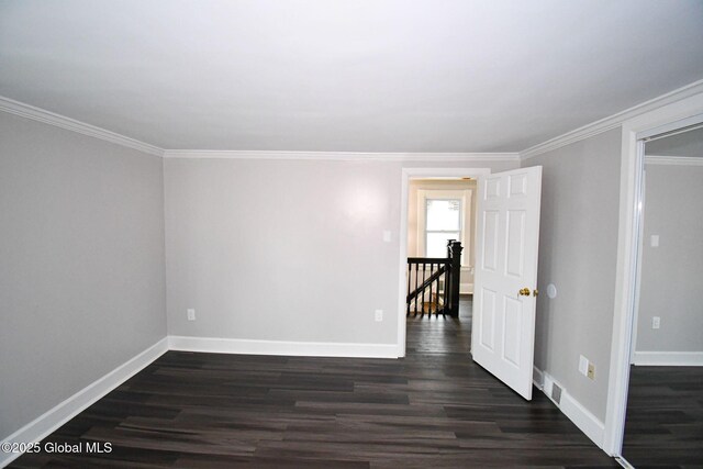 unfurnished room with baseboards, ornamental molding, and dark wood-style floors