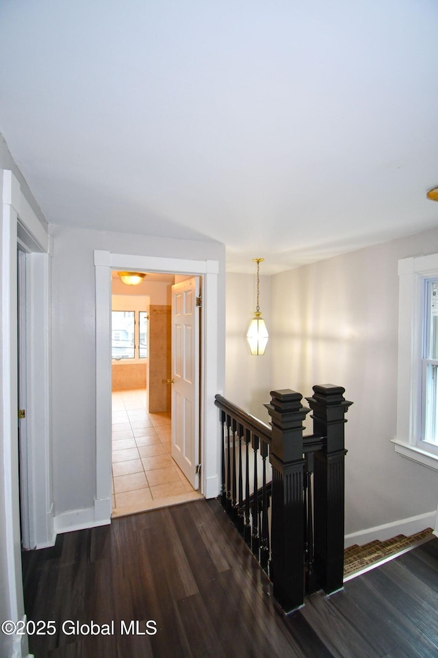hall featuring baseboards, an upstairs landing, and wood finished floors