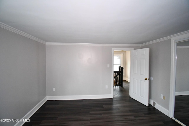 empty room with dark wood-type flooring, baseboards, and ornamental molding