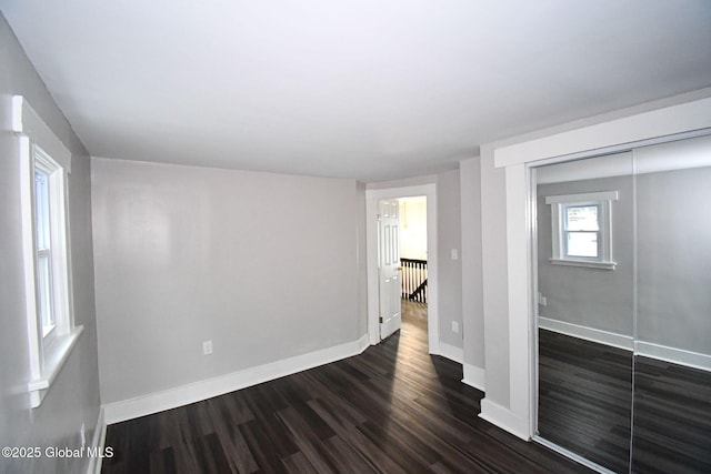 unfurnished room with baseboards and dark wood-style floors