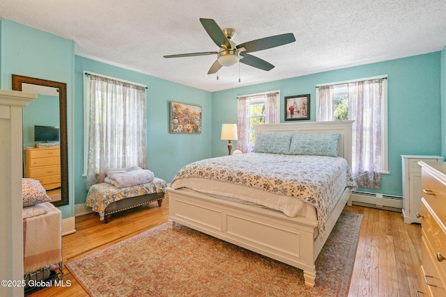 99 Otsego St, Canajoharie, NY 13317 - bedroom featuring baseboard heating, light wood-style flooring, a textured ceiling, and ceiling fan