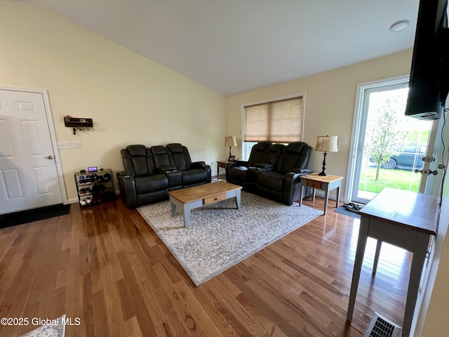 living area featuring lofted ceiling, wood finished floors, and baseboards