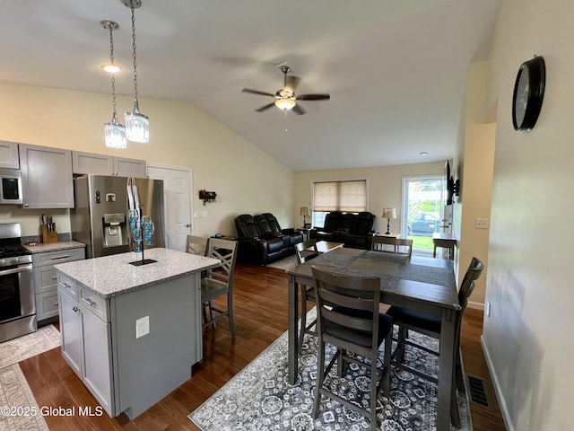 kitchen featuring stainless steel appliances, gray cabinets, a kitchen island, ceiling fan, and vaulted ceiling