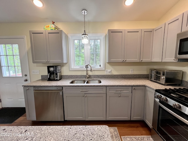 kitchen with stainless steel appliances, a sink, gray cabinetry, dark wood-style flooring, and recessed lighting
