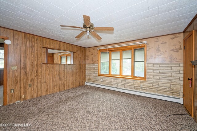 17-19 Smith Ct, North Greenbush, NY 12198 - empty room with baseboard heating, ceiling fan, wood walls, and carpet floors