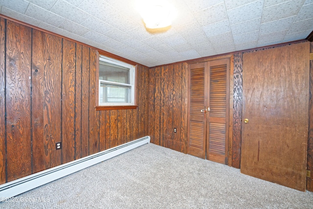 17-19 Smith Ct, North Greenbush, NY 12198 - unfurnished bedroom with a baseboard heating unit, carpet, a closet, and wood walls