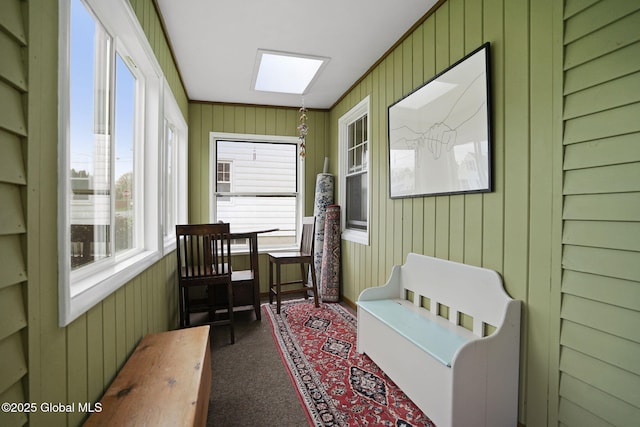 sunroom with wooden walls, a skylight, and carpet floors