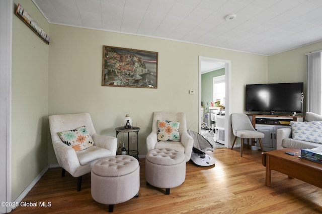 living area featuring wood finished floors and crown molding