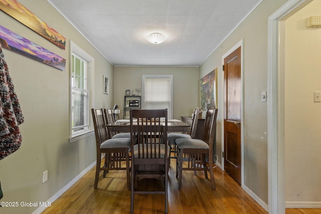 dining room featuring wood finished floors, crown molding, and baseboards