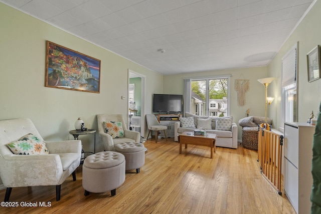 living area with ornamental molding and light wood-type flooring