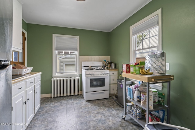 kitchen with radiator, white gas range oven, white cabinets, ornamental molding, and light countertops