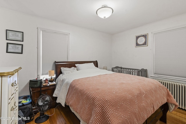 bedroom featuring radiator heating unit, wood finished floors, and ornamental molding