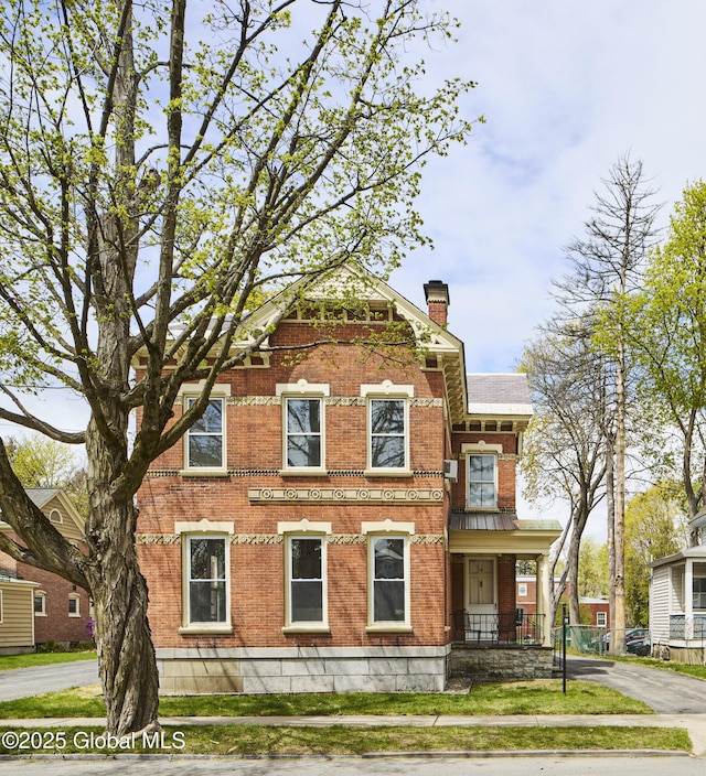 view of front facade with a chimney and brick siding