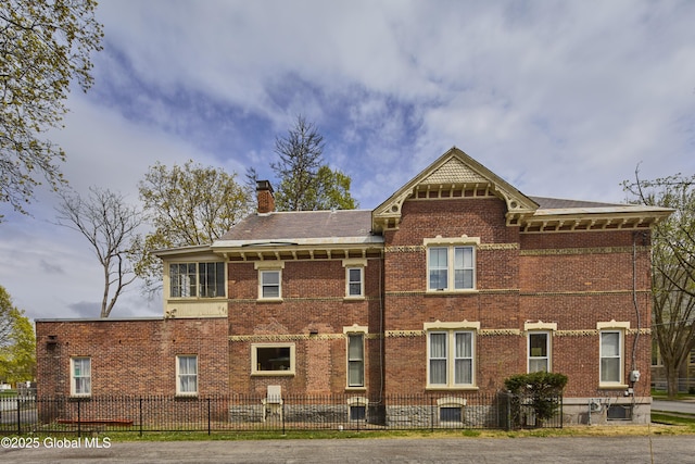 exterior space with a fenced front yard, brick siding, and a chimney
